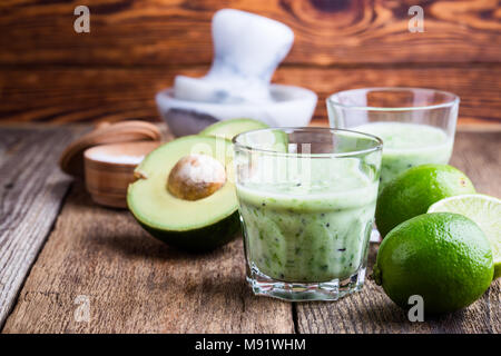 Cyril Lignac smoothie légumes vert style dans les verres avec des ingrédients de l'avocat et lime sur table en bois rustique, salé boisson laitière saine avec org Banque D'Images