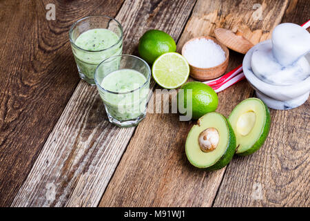 Cyril Lignac smoothie légumes vert style dans les verres avec des ingrédients de l'avocat et lime sur table en bois rustique, salé boisson laitière saine avec org Banque D'Images