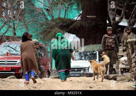 Srinagar, au Cachemire. Mar 21, 2018.Les policiers indiens montent la garde comme femmes cachemiries balade , au cours d'une fusillade entre le gouvernement et les militants à Halmatpora Kupwara, quelque 95 km (60 milles) au nord de Srinagar.Quatre soldats indiens et quatre militants présumés ont été tués dans un gunbattle près de la frontière de fait entre l'Inde et le Pakistan dans la région contestée du Cachemire le mercredi, un haut responsable de la police a dit.©Sofi Suhail/Alamy Live News Banque D'Images