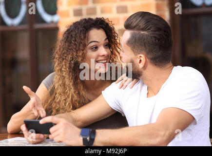 Couple heureux en utilisant un smartphone assis en terrasse Banque D'Images