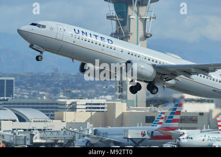 La Photo en gros plan d'un United Airlines Boeing 737-800 Avion de ligne au décollage de l'Aéroport International de Los Angeles, LAX, la tour de contrôle derrière. Banque D'Images