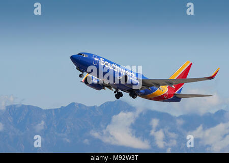 Southwest Airlines Boeing 737 avion de décoller de l'Aéroport International de Los Angeles, LAX, de nuages et de neige couverts montagnes San Gabriel derrière. Banque D'Images