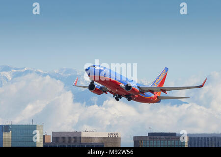 Southwest Airlines Boeing 737 Avion au décollage de l'Aéroport International de Los Angeles, LAX, de nuages et de neige couverts montagnes San Gabriel derrière. Banque D'Images