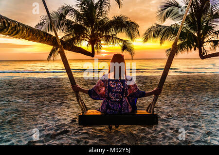 Vue sur le coucher du soleil le swing femme enjoing par Beach sur Koh Kood island en Thailande Banque D'Images