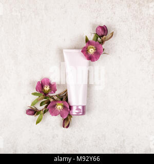 Produit cosmétique rose mise en page avec des fleurs rouge sur shabby chic rustique en pierre fond beige. Concept beauté de luxe avec le tube de crème, vue d'en haut, l' Banque D'Images
