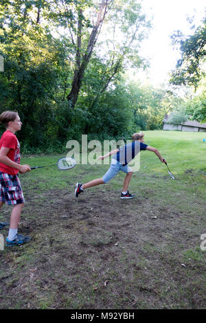 Teenage boy s'étend pour revenir volant dans un jeu de badminton de l'herbe. Clitherall Minnesota MN USA Banque D'Images