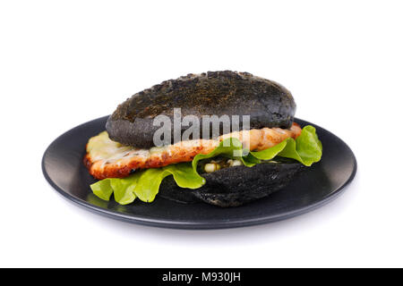 Hamburger fraîchement préparé avec le rouleau de couleur noire, les légumes et le saumon escalope. Sandwich Maison isolé sur fond blanc Banque D'Images
