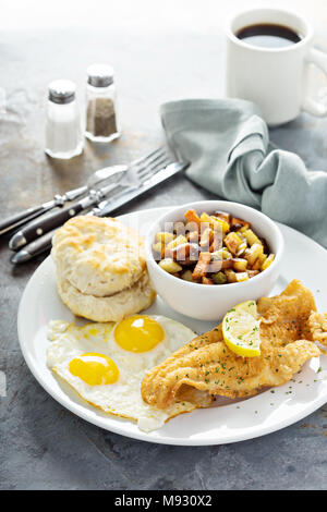 Déjeuner de poisson frit avec des oeufs au plat, de biscuit et de pommes de terre Banque D'Images