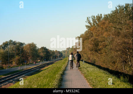 Varsovie, Pologne  : vue arrière de l'homme et de la femme la bicyclette le long de la voie pavée, par campagne polonaise. Scène d'automne tranquille au crépuscule Banque D'Images