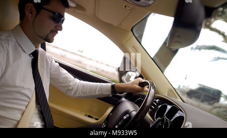 Jeune homme d'affaires dans la conduite, lunettes de voiture cool elite service de transport Banque D'Images