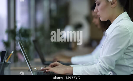 Beautiful woman typing on laptop, travailler sur projet d'entreprise avec l'accent face Banque D'Images