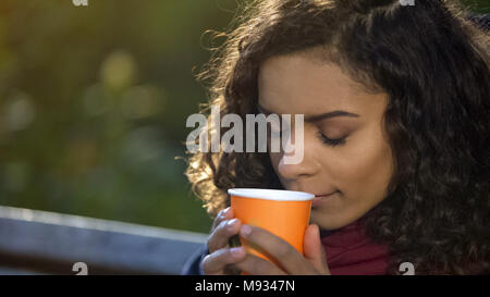 Jeune femme aux cheveux bouclés appréciant le goût de café du matin à l'extérieur préférés Banque D'Images