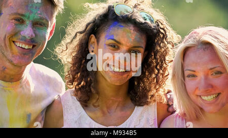 Heureux les jeunes gens avec le visage couvert de couleurs, friends smiling for camera Banque D'Images
