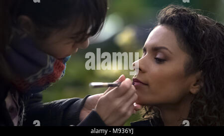 Make-up artist appliquer le rouge à lèvres sur les modèles des lèvres, de la beauté naturelle de dame biracial Banque D'Images