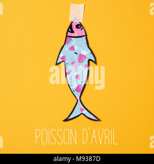 Un poisson de papier, faite par moi-même, attaché avec du ruban adhésif pour un fond orange et le texte poisson d avril, April Fools Day en français Banque D'Images