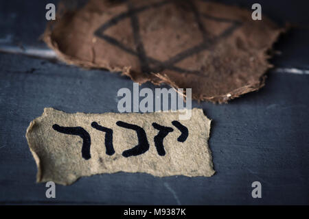 Libre d'un insigne et un juif déchiqueté feuille de papier jaunâtre avec le mot yizkor, rappelez-vous en hébreu et le nom d'une prière en mémoire du décès Banque D'Images