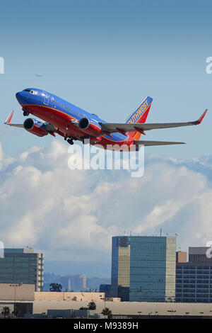 Southwest Airlines Boeing 737 avion de décoller de l'Aéroport International de Los Angeles, LAX, de nuages et de neige couverts montagnes San Gabriel derrière. Banque D'Images