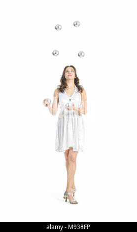 Une jeune femme artiste de cirque, jongle avec des balles en argent. Studio shot sur fond blanc, isolé de l'image. Banque D'Images