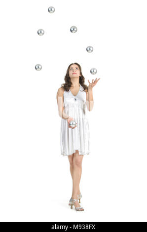 Une jeune femme artiste de cirque, jongle avec des balles en argent. Studio shot sur fond blanc, isolé de l'image. Banque D'Images