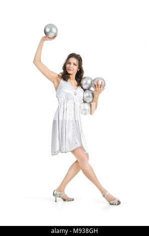 Une jeune femme artiste de cirque, jongle avec des balles en argent. Studio shot sur fond blanc, isolé de l'image. Banque D'Images