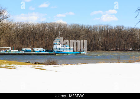 À la cour couverte de neige à l'Hudson River, du sud de l'Albany NY en hiver. Tug boat couleur sarcelle barge poussée jusqu'à la rivière du nord. Banque D'Images