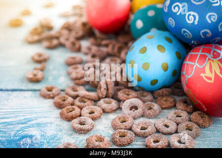 Les oeufs de Pâques colorés et anneaux de maïs doux sur fond de bois. Joyeuses Pâques Banque D'Images