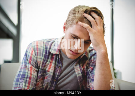 Libre de la tête dans les mains assis contre fond blanc Banque D'Images