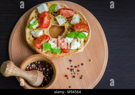 Frisella classique tomate, fromage mozzarella et basilic. Friselle démarreur italien. Pain séché appelé freselle sur planche de bois. Cuisine italienne. V en bonne santé Banque D'Images