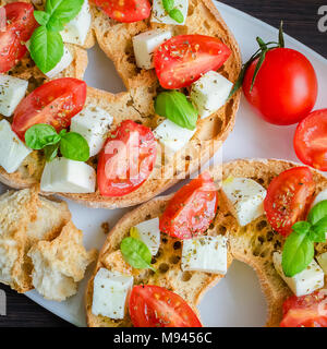 Friselle démarreur italien. Frisella classique tomate, fromage mozzarella et basilic et d'origan et d'huile d'olive. Pain séché appelé freselle sur blanc plat Banque D'Images