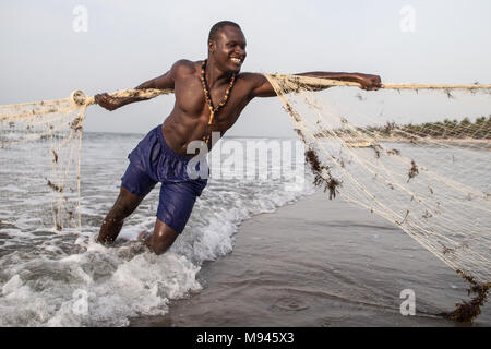 Les pêcheurs dans le village côtier de Kotu, Gambie, tirer dans leur filet de pêche dans l'espoir d'attraper le barracuda pour les touristes. Banque D'Images