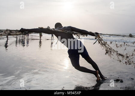 Les pêcheurs dans le village côtier de Kotu, Gambie, tirer dans leur filet de pêche dans l'espoir d'attraper le barracuda pour les touristes. Banque D'Images