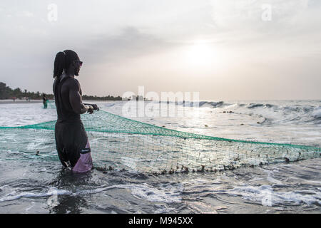 Les pêcheurs dans le village côtier de Kotu, Gambie, tirer dans leur filet de pêche dans l'espoir d'attraper le barracuda pour les touristes. Banque D'Images