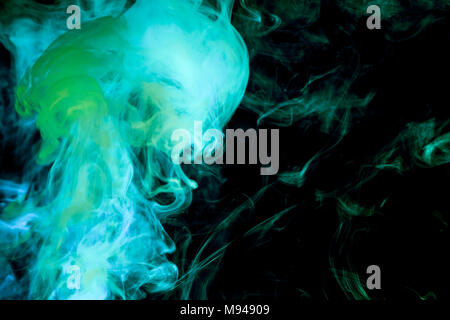 La fumée multicolore dense de couleurs bleu et vert sur un fond noir isolé. Contexte de la fumée vape Banque D'Images