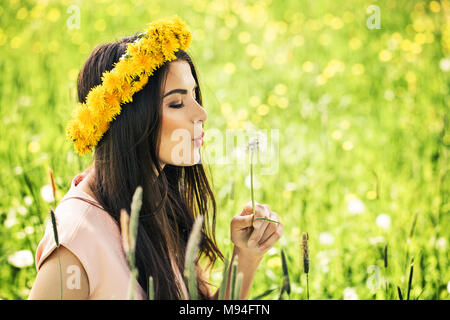 Femme sans souci avec un pissenlit sur l'herbe verte. Heureux Mannequin portant des fleurs jaunes à l'extérieur Banque D'Images