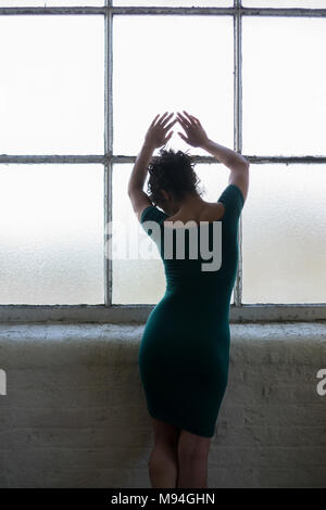 Vue arrière d'un seul femme debout par la fenêtre les mains de toucher le verre Banque D'Images