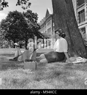 Les étudiants du collège femmes lounge sur une pelouse du campus de l'Illinois, ca. 1958. Banque D'Images