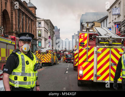 Hope Street, Glasgow, Ecosse, Royaume-Uni, 22 mars 2018. Un incendie majeur impliquant de multiples bâtiments ferme rues dans le centre de Glasgow. Les moteurs de l'incendie participer à l'incident. Un policier porte un masque en raison du risque de l'amiante de la fumée Banque D'Images