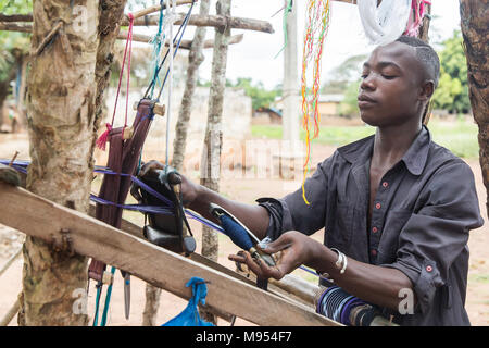 Kouassi, 15 ans, travaille dans une petite usine de tissage dans Gbomi Kondeyaokro, centre de la Côte d'Ivoire. Il s'agit d'un Akan, célèbres pour leur tissu Kente (connu comme nwentom Akan) dans laquelle un type de soie et coton tissus faits de bandes de toile tissée. Banque D'Images