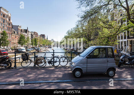 AMSTERDAM, Pays-Bas - le 27 mai 2017 : vue sur le canal de l'eau et des petites voitures en stationnement des vélos sur la rue Singel und le 27 mai 2017. Amsterdam est popula Banque D'Images