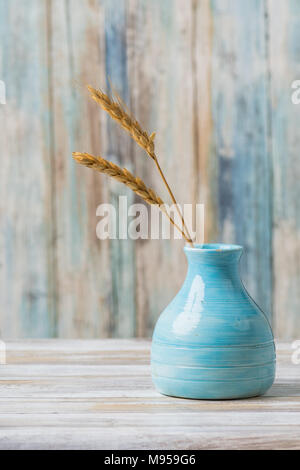 Vase poterie bleu avec des tiges de blé et de bois contexte Banque D'Images