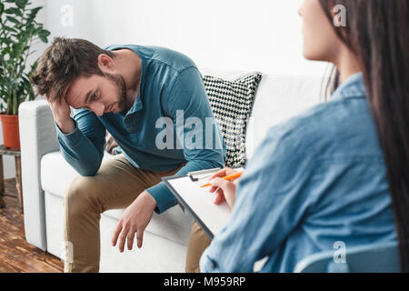 L'homme avec le psychologue problèmes de rapport de concept scrratching la pensée réfléchie de la tête de sa femme alors que le diagnostic d'écriture femme clo Banque D'Images