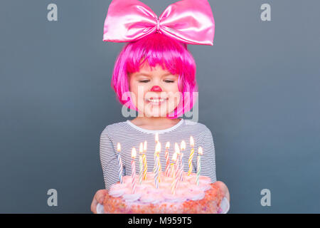 Funny Girl regarde le gâteau et veut manger. Studio shot, isolé sur fond gris Banque D'Images