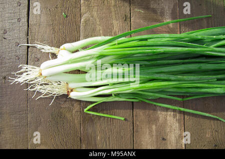 Bande d'oignons verts frais sur une vieille table en bois Banque D'Images