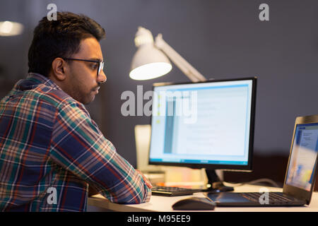 L'homme créatif travaillant avec un ordinateur portable à l'office de nuit Banque D'Images