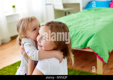 Heureux les petites filles ou soeurs hugging at home Banque D'Images