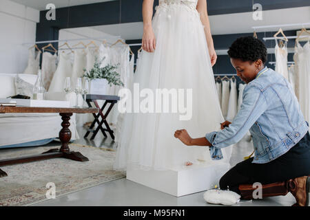 Concepteur de robe de mariage femme d'effectuer le réglage de robe nuptiale dans son studio. Bride standing dans sa robe femme adjustme avec couturière de décisions Banque D'Images