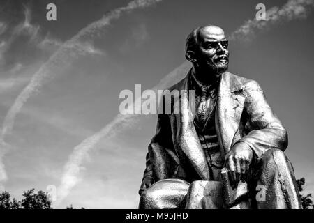 Une image en noir et blanc d'une statue de Lénine dans un square près de St Petersbourg, avec des traînées d'avions dans le ciel. Banque D'Images