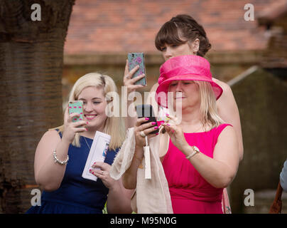 Clientèle féminine à prendre des photos de mariage sur les téléphones mobiles Banque D'Images