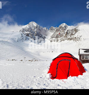 La ligne rouge vif tente sur la neige avec pic Lomnicky Stit dans l'arrière-plan, sur une journée d'hiver ensoleillée. Station de ski de Tatranská Lomnica, Slovaquie Banque D'Images