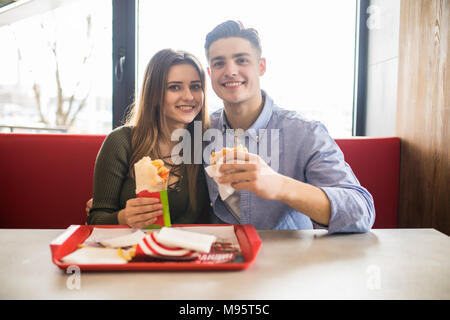 Heureux couple eating fast food burger et döner dans fast food cafe Banque D'Images